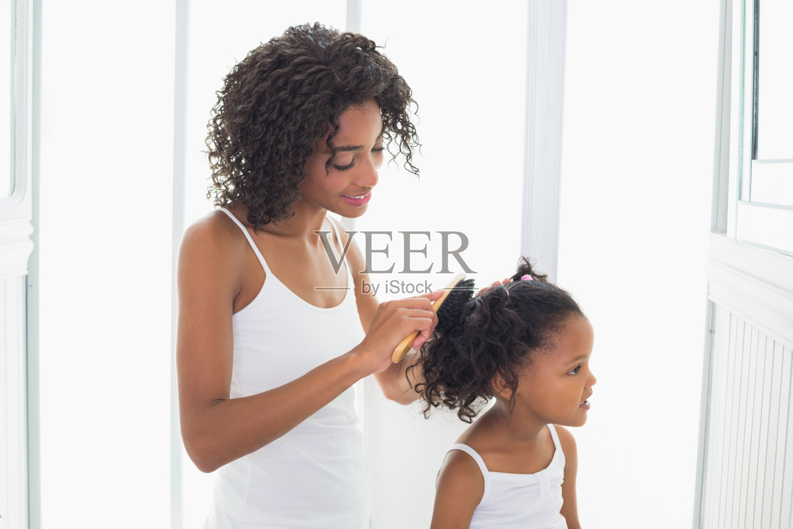 漂亮的母亲在梳理女儿的头发照片摄影图片