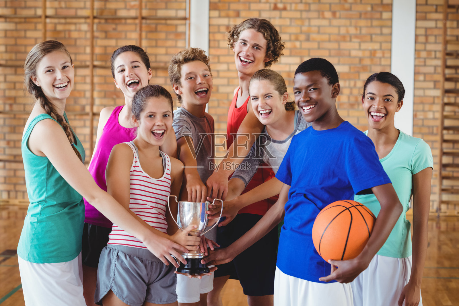 高中的孩子们在篮球场上拿着奖杯微笑着照片摄影图片