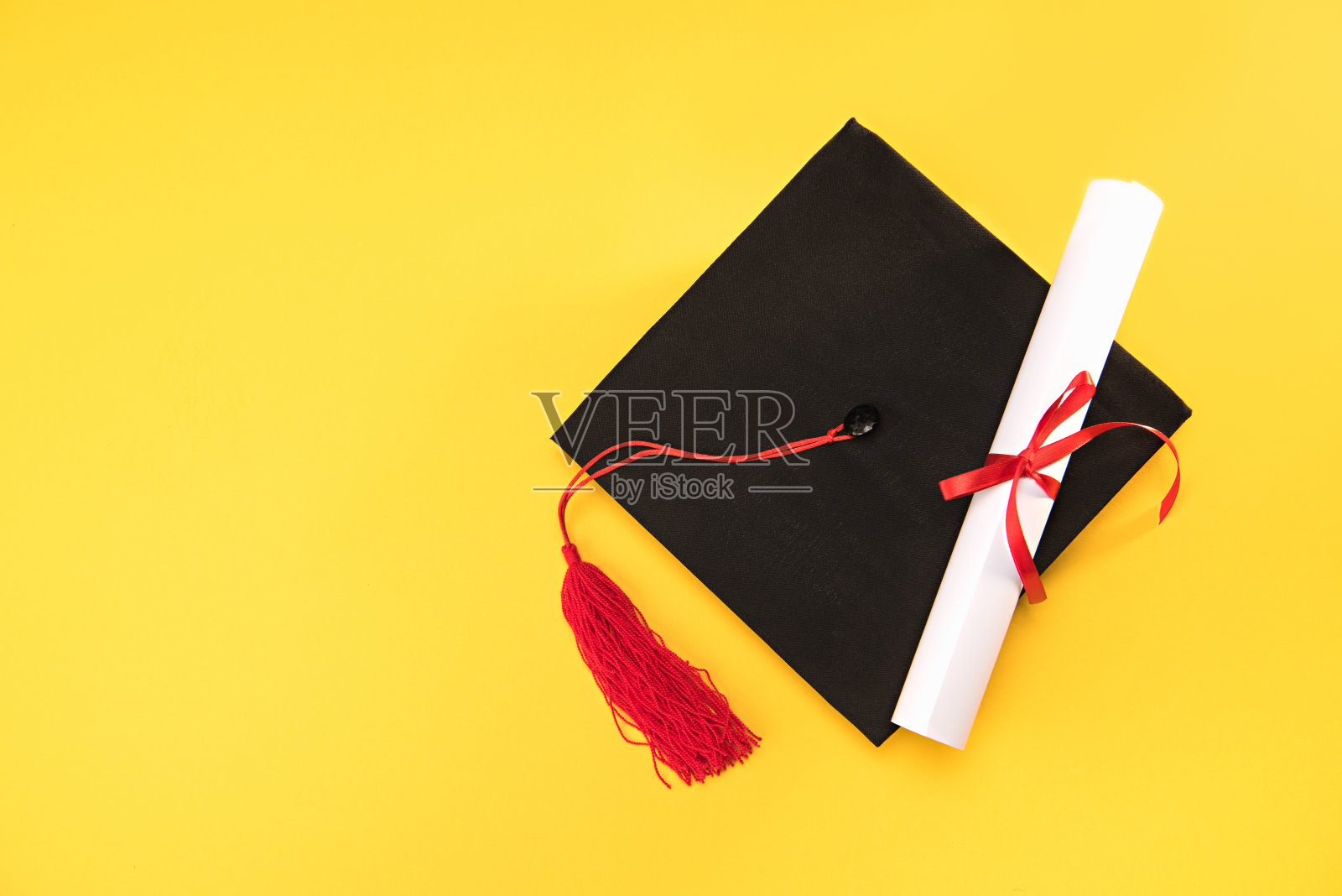 俯视毕业学位帽和毕业证书上的黄色背景，教育理念照片摄影图片