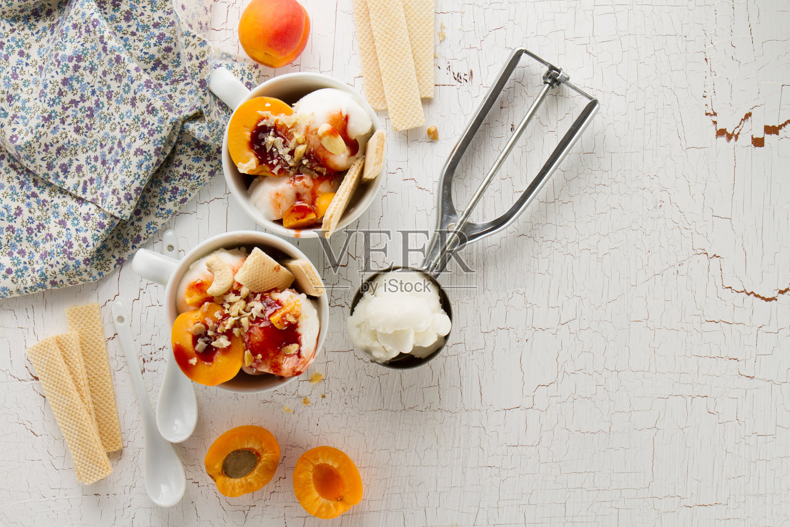 美味的新鲜冷开胃香草冰淇淋与坚果，杏子，华夫饼和糖浆在白色的桌子上制作甜点的原料。前视图。照片摄影图片