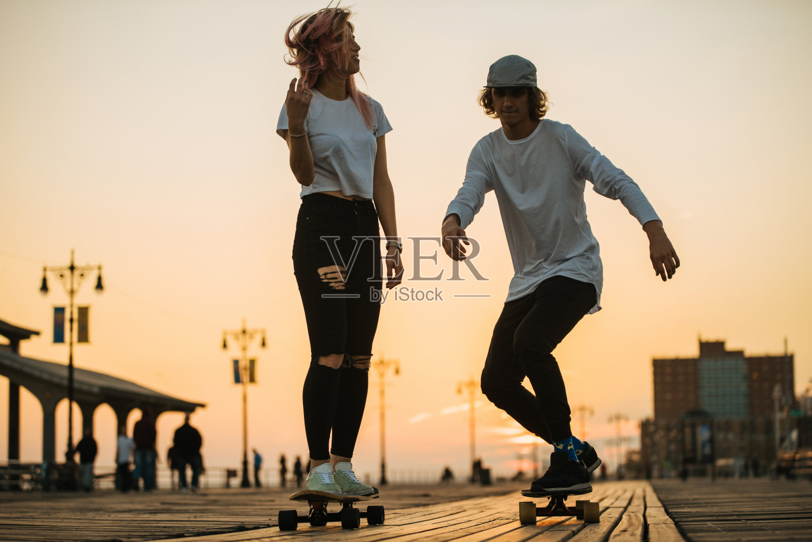 十几岁的情侣在木板路上骑长木板照片摄影图片