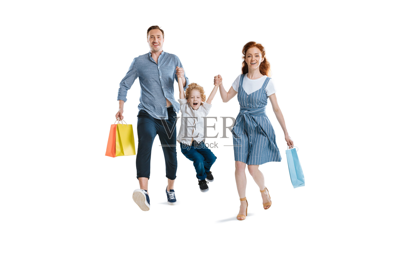 幸福的年轻家庭与一个孩子拿着购物袋和微笑的镜头孤立在白色照片摄影图片