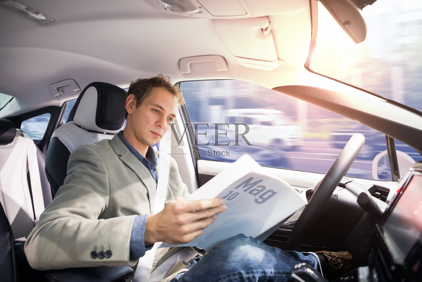 白人司机开着自动驾驶汽车看杂志。自己驾驶车辆。无人驾驶的车。照片摄影图片