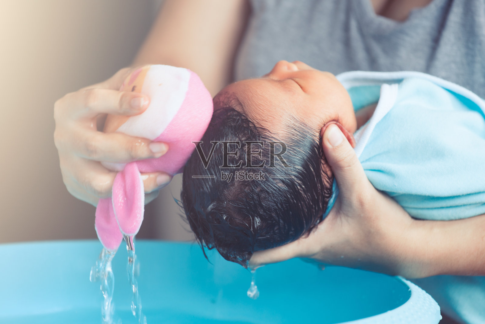 可爱的亚洲新生女婴在洗澡。妈妈用海绵清洁婴儿的头发照片摄影图片