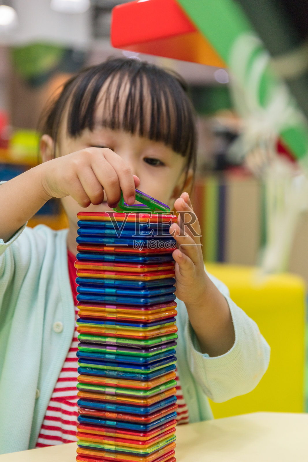 亚洲华人小女孩玩彩色磁铁塑料积木套件照片摄影图片