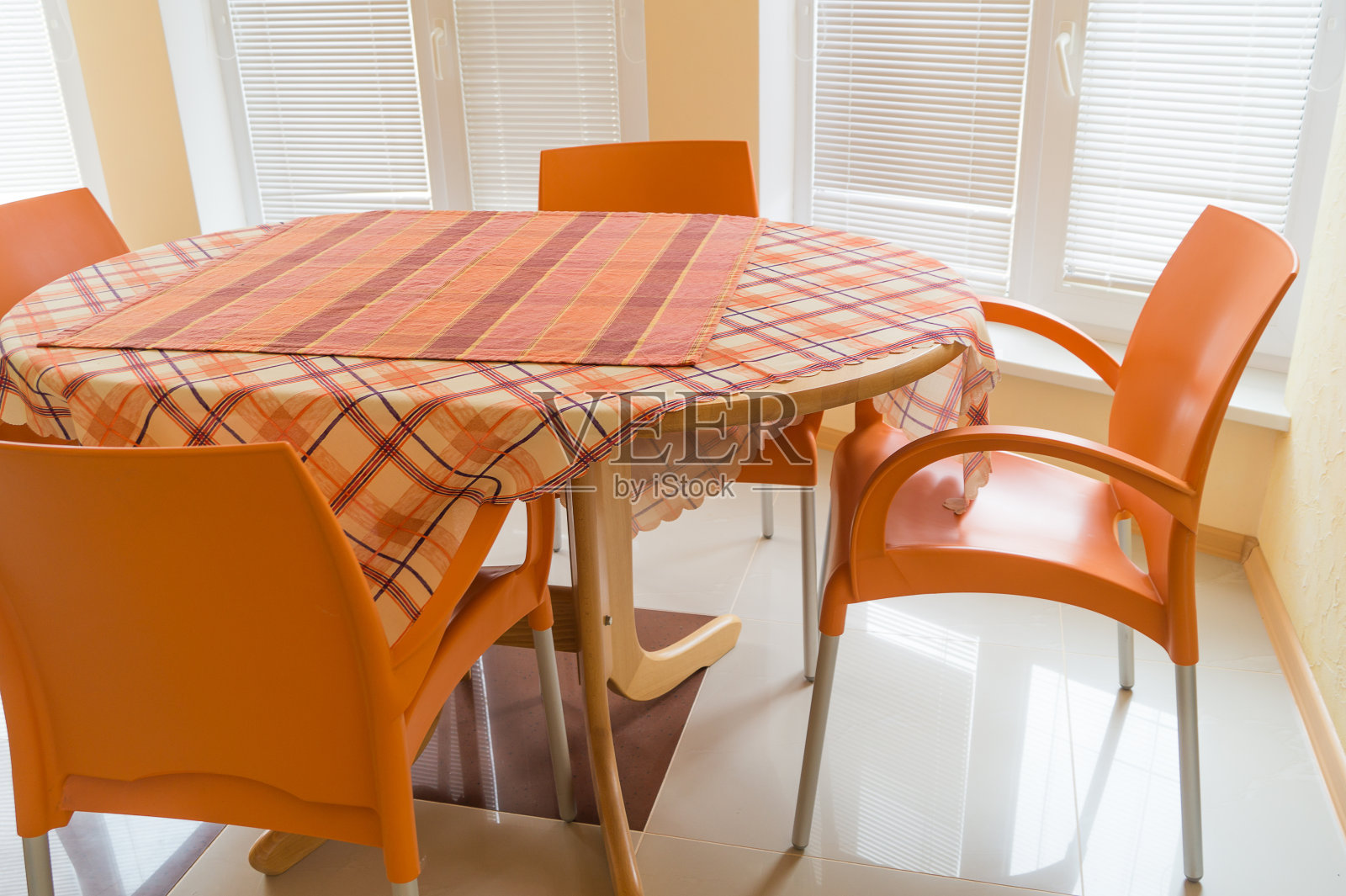 餐厅里有四把橙色的椅子和铺着格子桌布的桌子照片摄影图片