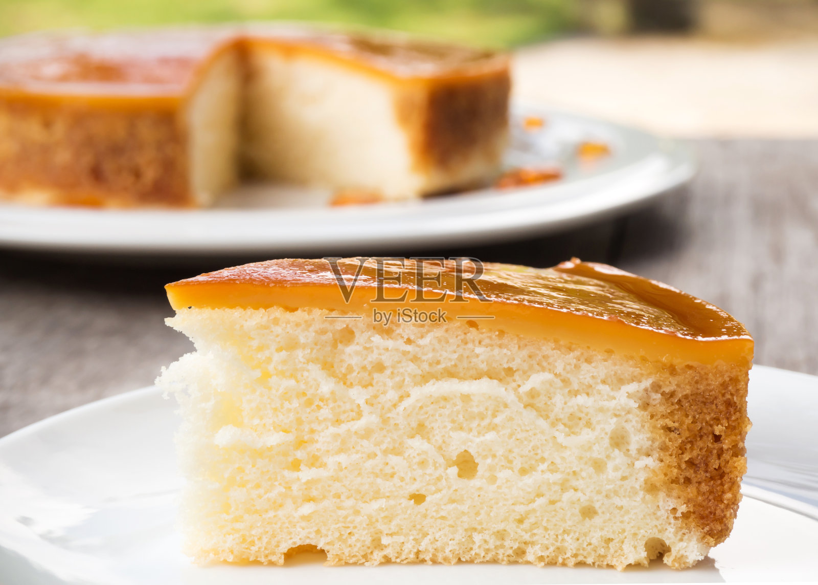 白盘子上的切焦糖蛋奶蛋糕。甜而潮湿的甜点。照片摄影图片