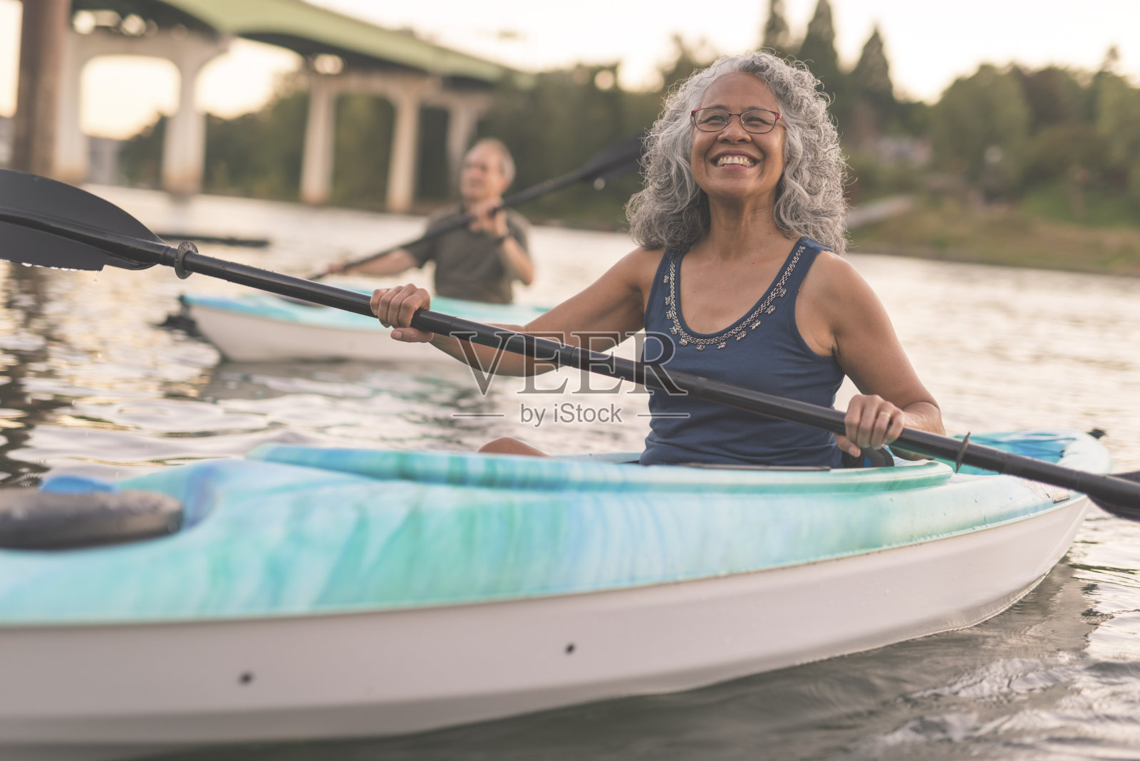 一位少数民族年长妇女微笑着和她的丈夫划皮划艇照片摄影图片