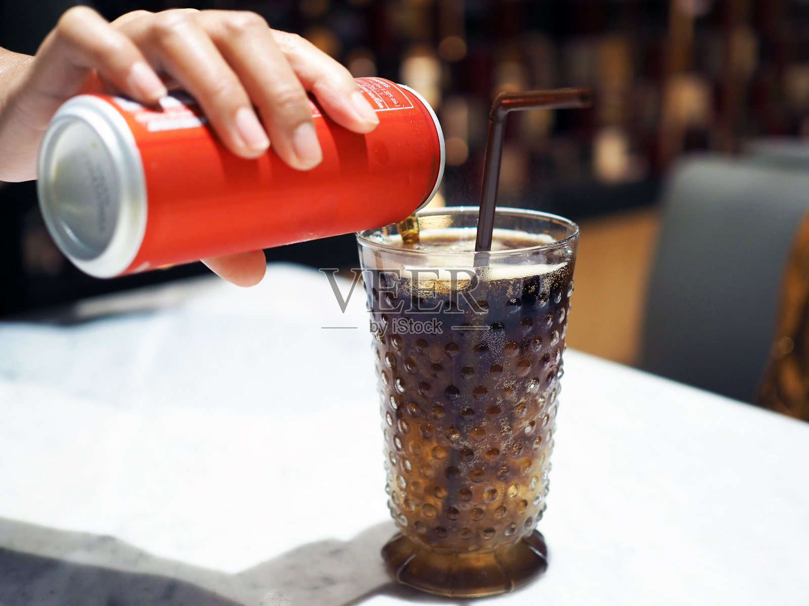 用吸管将可乐倒入冰块中。照片摄影图片