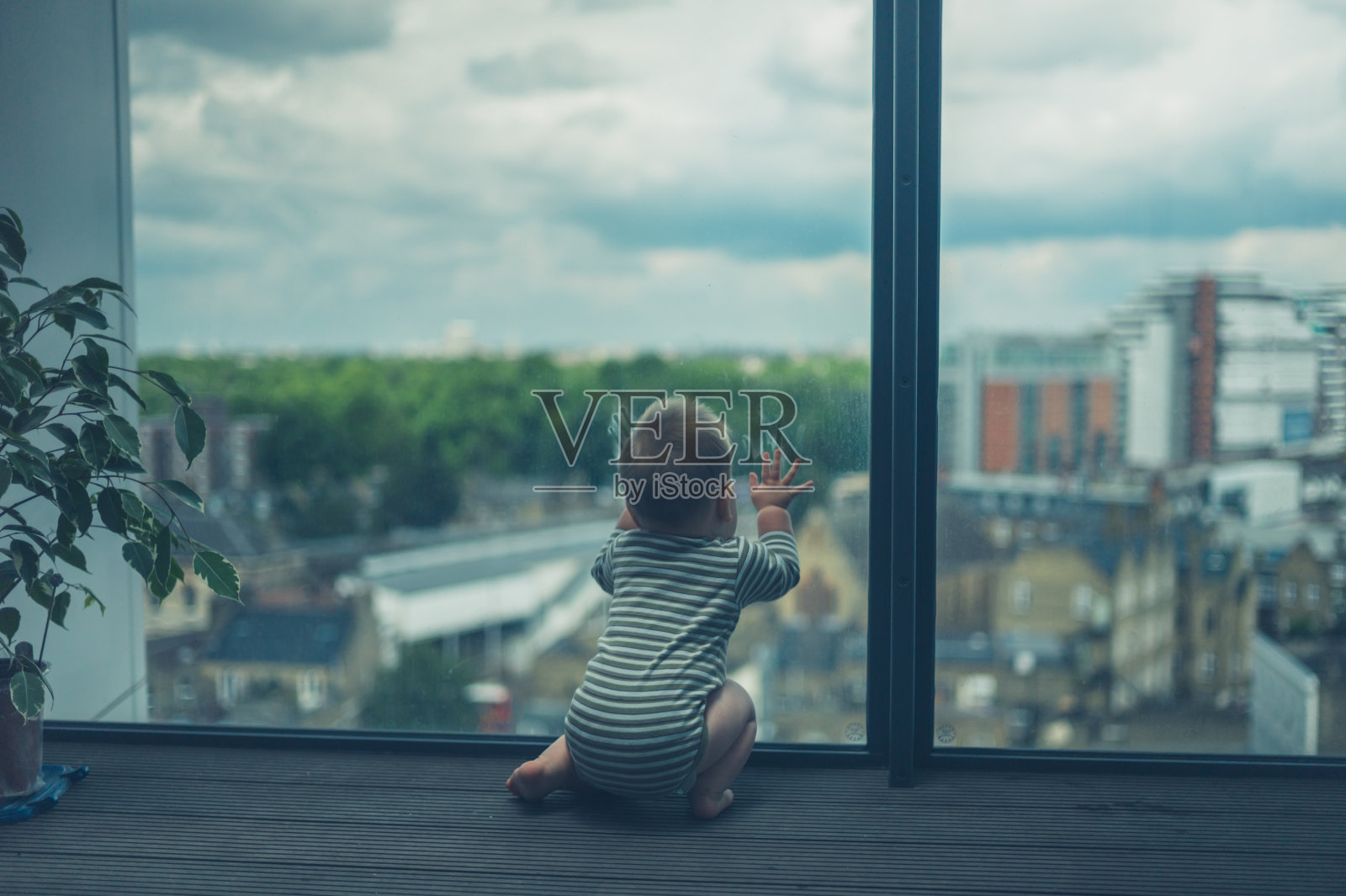 小婴儿坐在城市的阳台上照片摄影图片