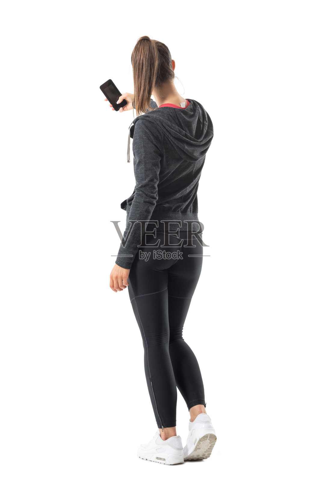 年轻的运动健康的女人用智能手机拍照的背影。照片摄影图片