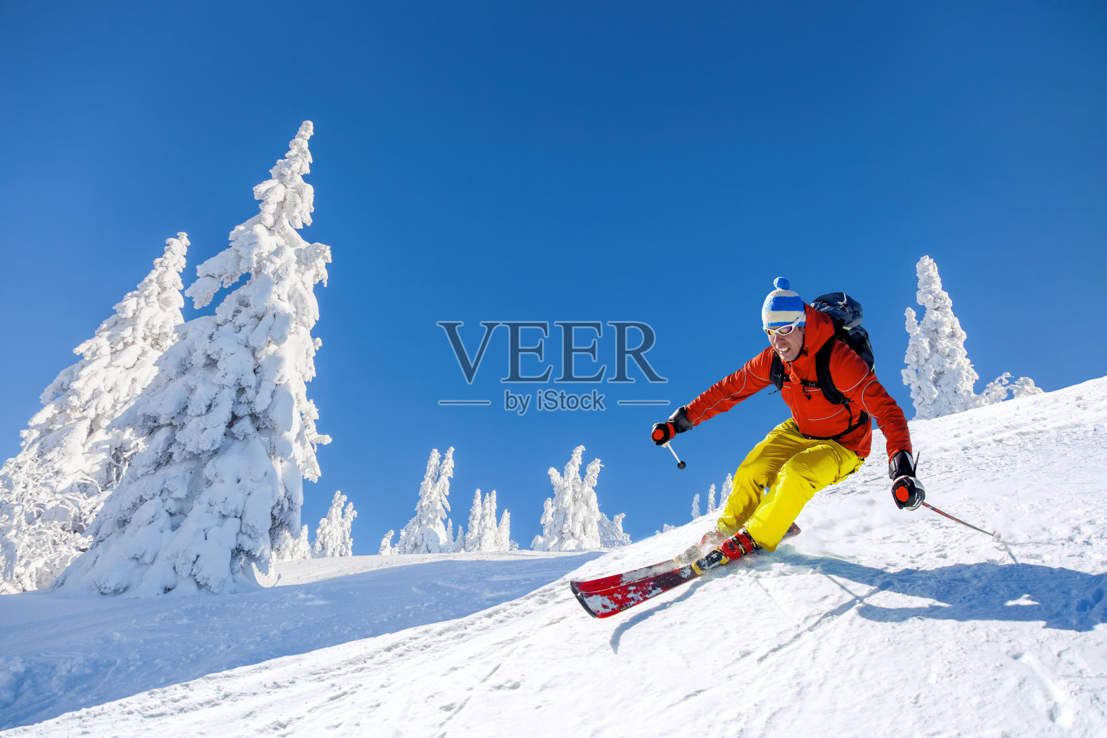 滑雪者在蓝天的映衬下，在高山中滑雪下山照片摄影图片