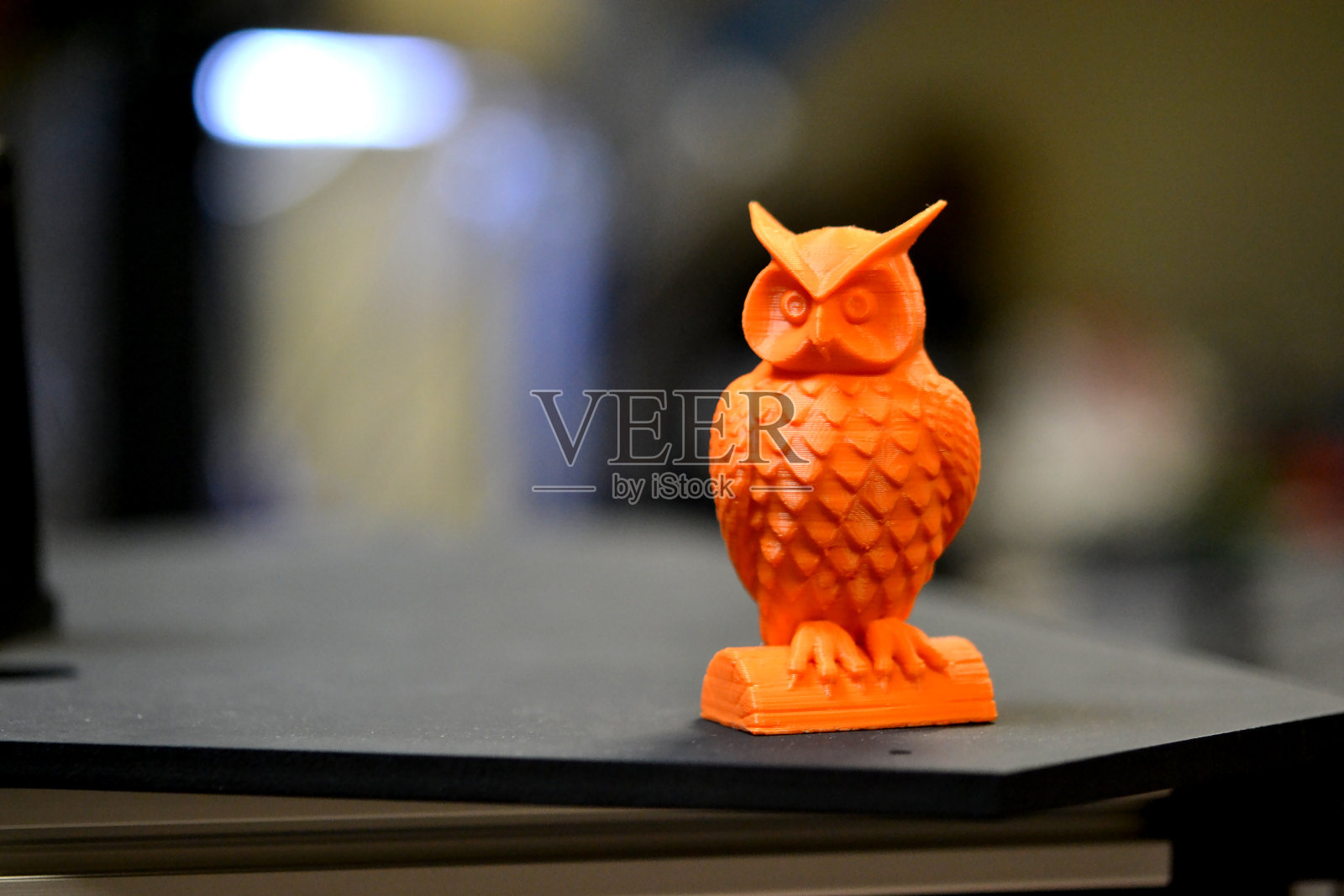 用3d打印机打印出的橙色猫头鹰物体站在模糊的黑色背景上照片摄影图片
