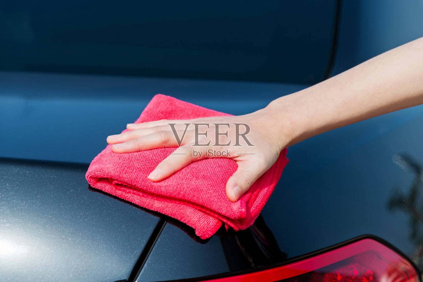 女人用红毛巾用手擦着车照片摄影图片