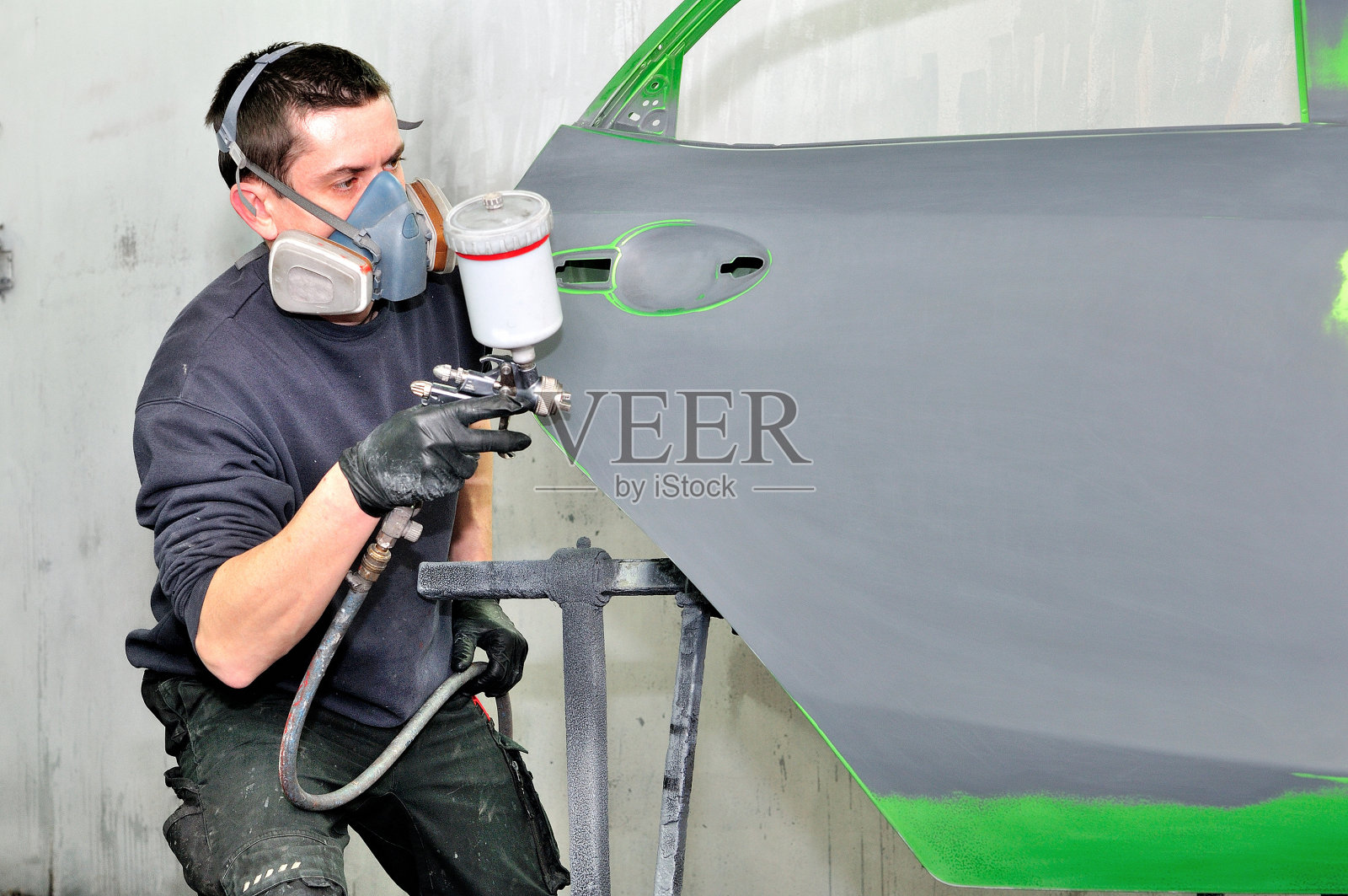 专业的汽车油漆工在绿色的门上工作。照片摄影图片