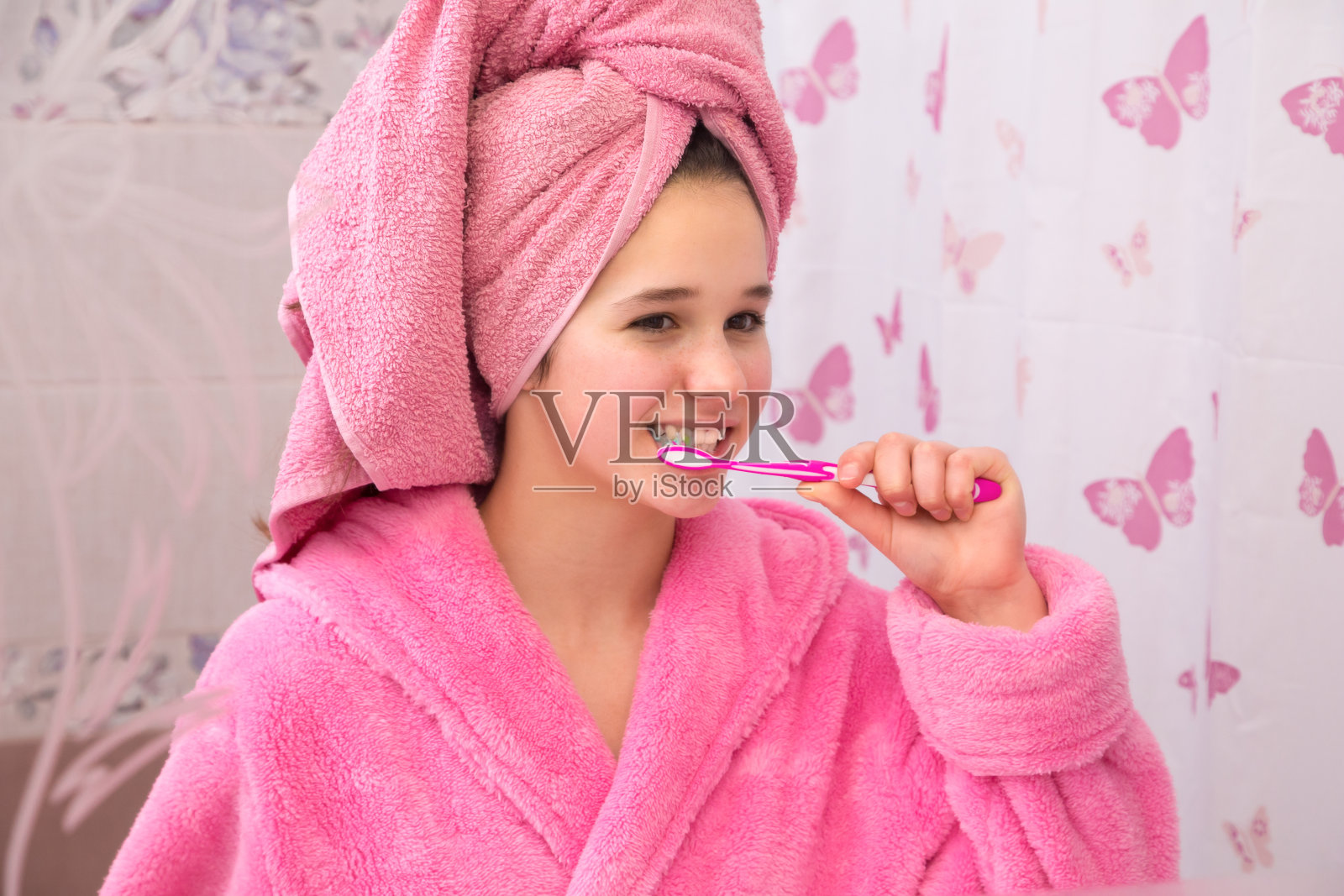 穿着浴袍的小女孩在浴室里刷牙照片摄影图片