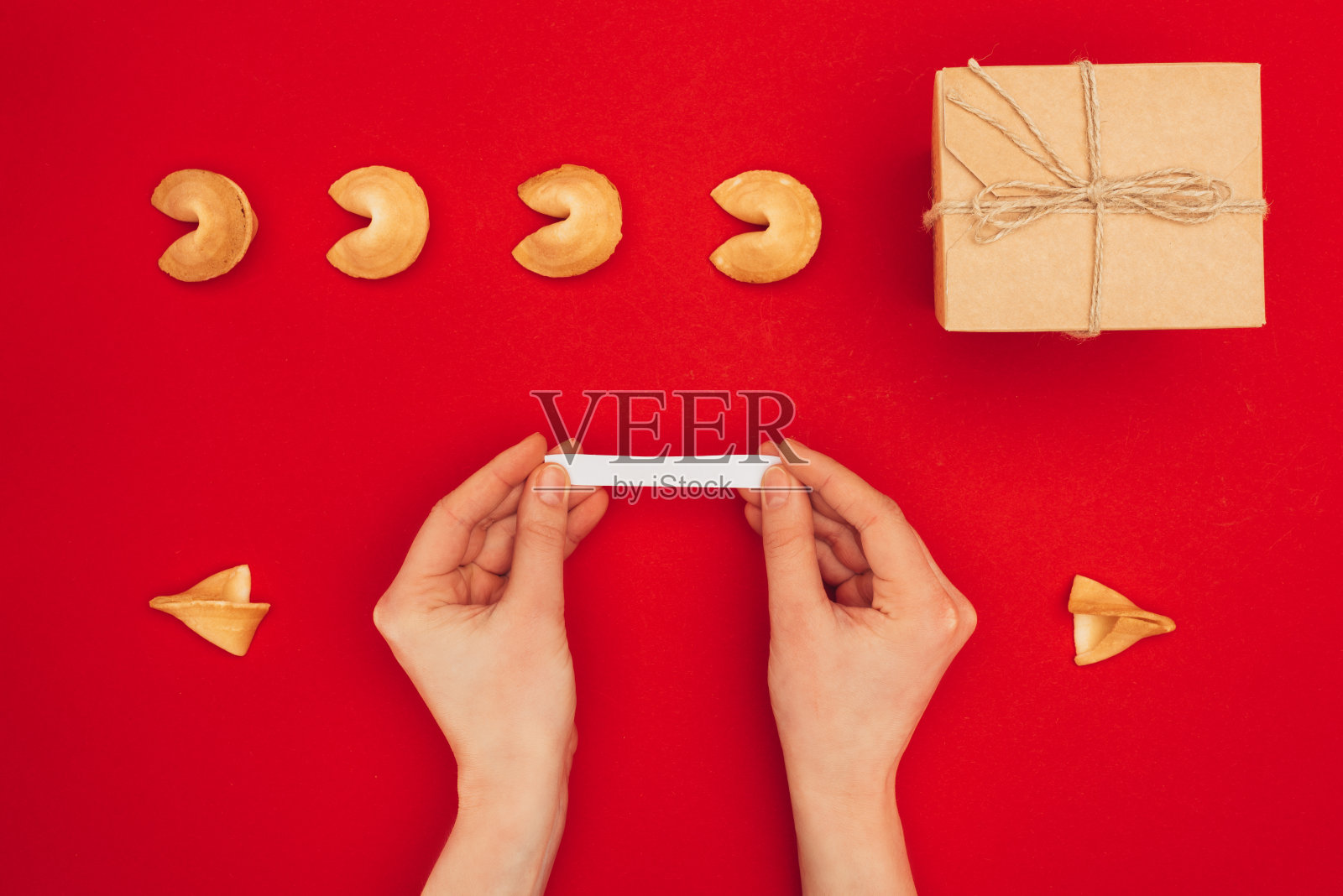 剪短的镜头女人打开幸运饼干在红色的表面，中国新年的概念照片摄影图片