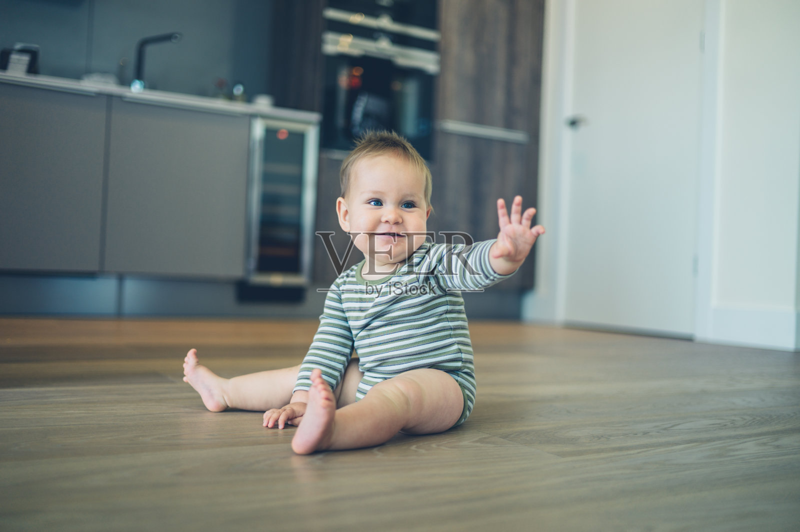 小婴儿在厨房地板上挥手照片摄影图片