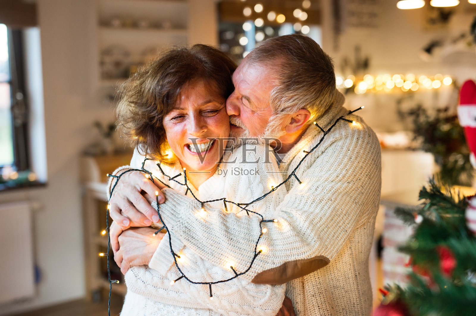 一对老年夫妇在圣诞节期间在家拥抱。照片摄影图片