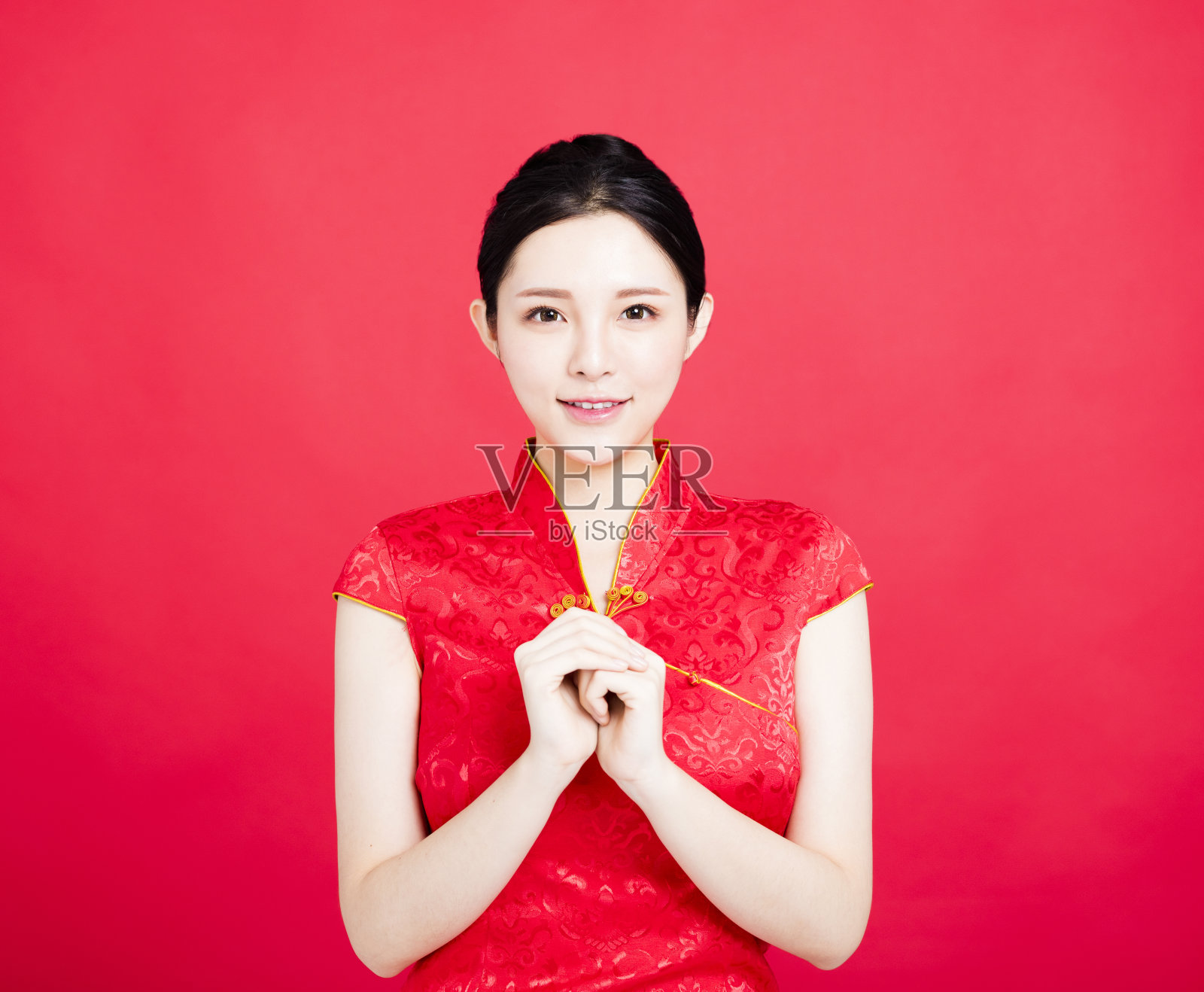 亚洲妇女穿着中国旗袍，摆着祝贺的姿势照片摄影图片