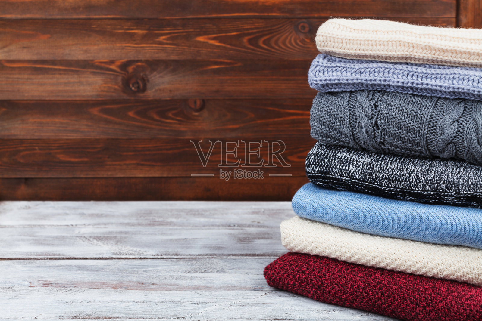 木制背景上的针织冬衣和羊毛衫。销售和折扣的概念。照片摄影图片