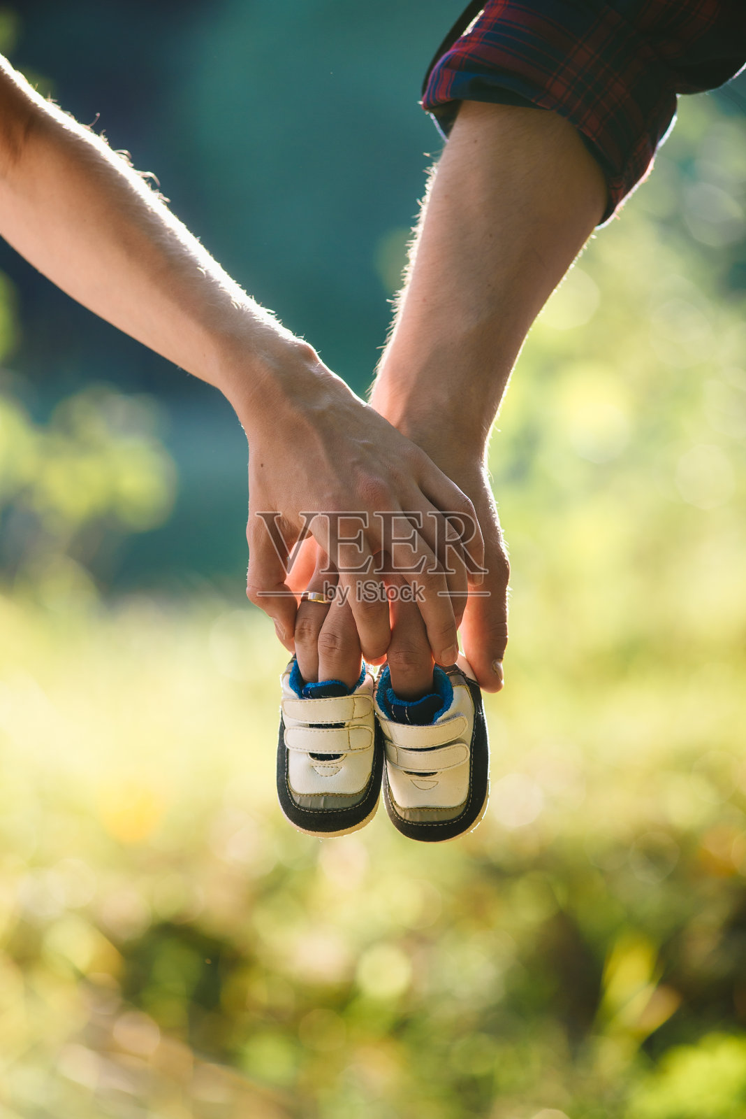 快乐的爸爸和妈妈手里拿着他们未来第一个孩子的婴儿鞋照片摄影图片