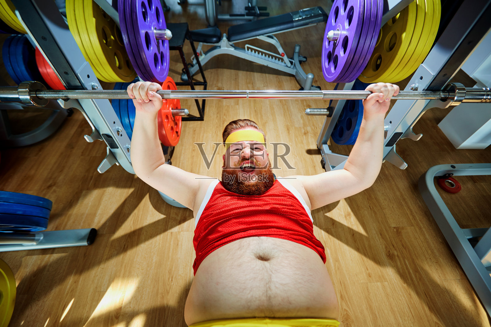 在健身房里用杠铃锻炼的胖子照片摄影图片