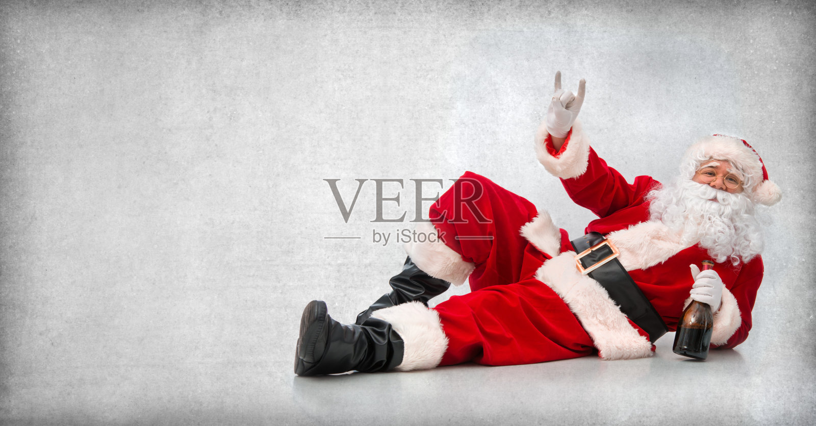 快乐的圣诞老人躺在地板上拿着一瓶酒照片摄影图片