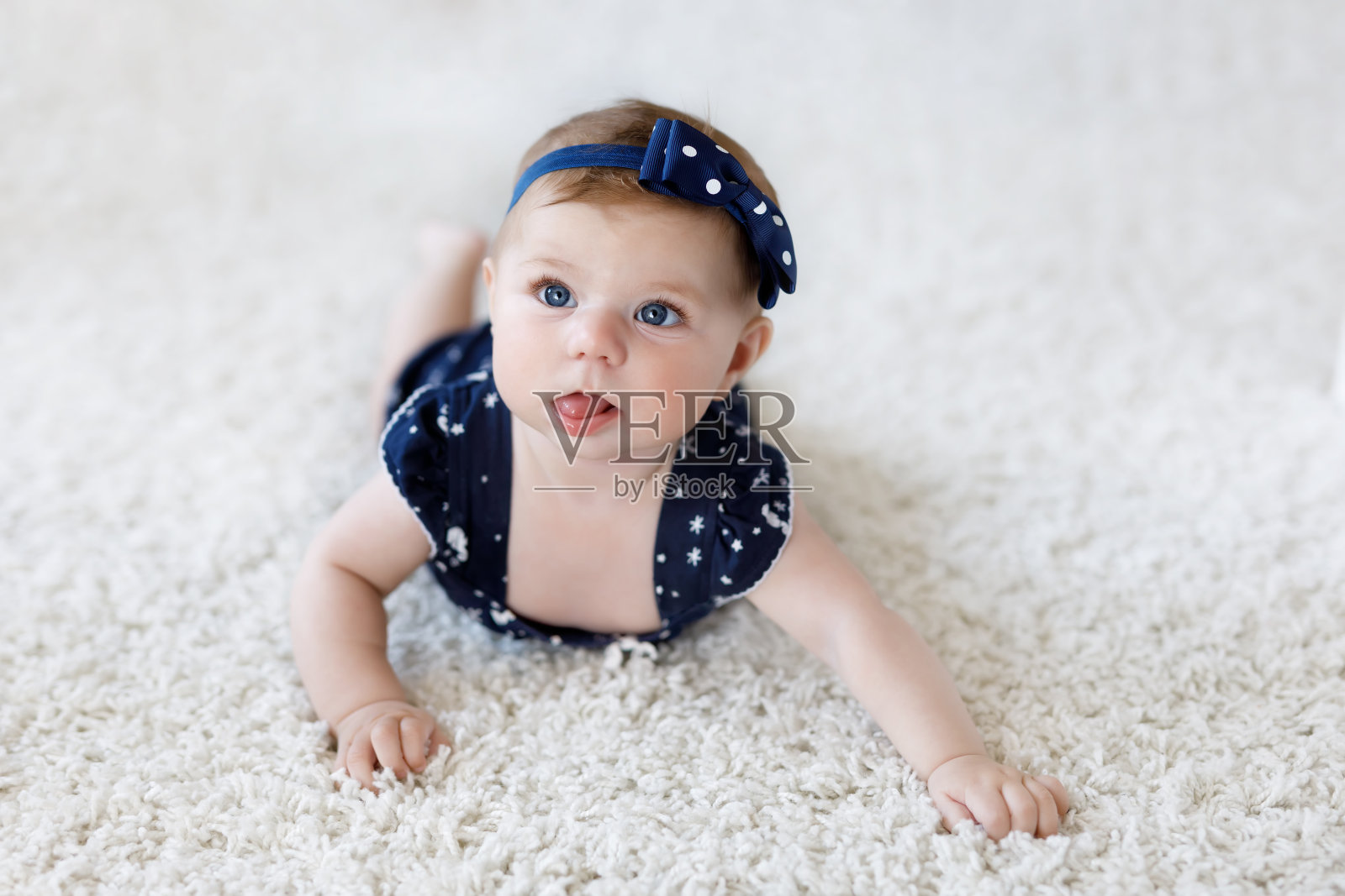 可爱可爱的小女孩穿着蓝色的衣服和头巾。照片摄影图片