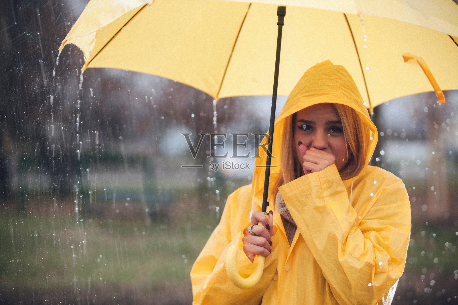 金发女人在雨中咳嗽，拿着伞照片摄影图片