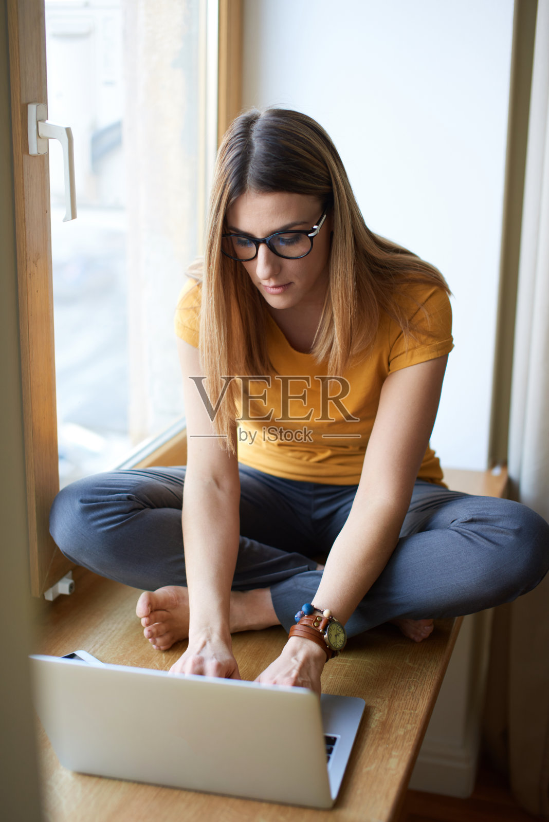 年轻女子在窗台上的电脑前工作照片摄影图片