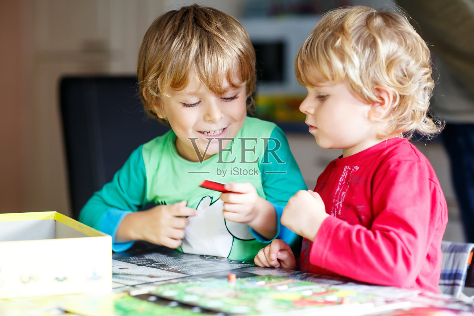 两个金发小男孩在家里玩棋盘游戏。有趣的兄弟姐妹玩得开心。照片摄影图片