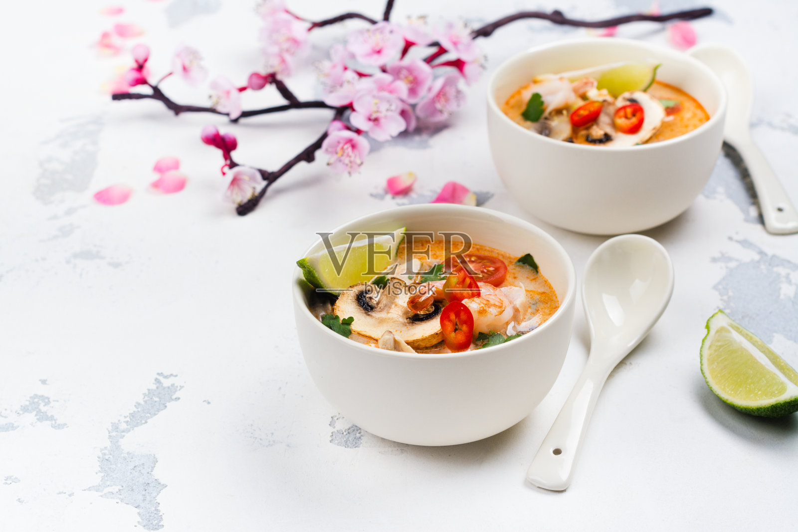 传统冬阴汤与盛开的樱花枝在白色的石头桌上照片摄影图片