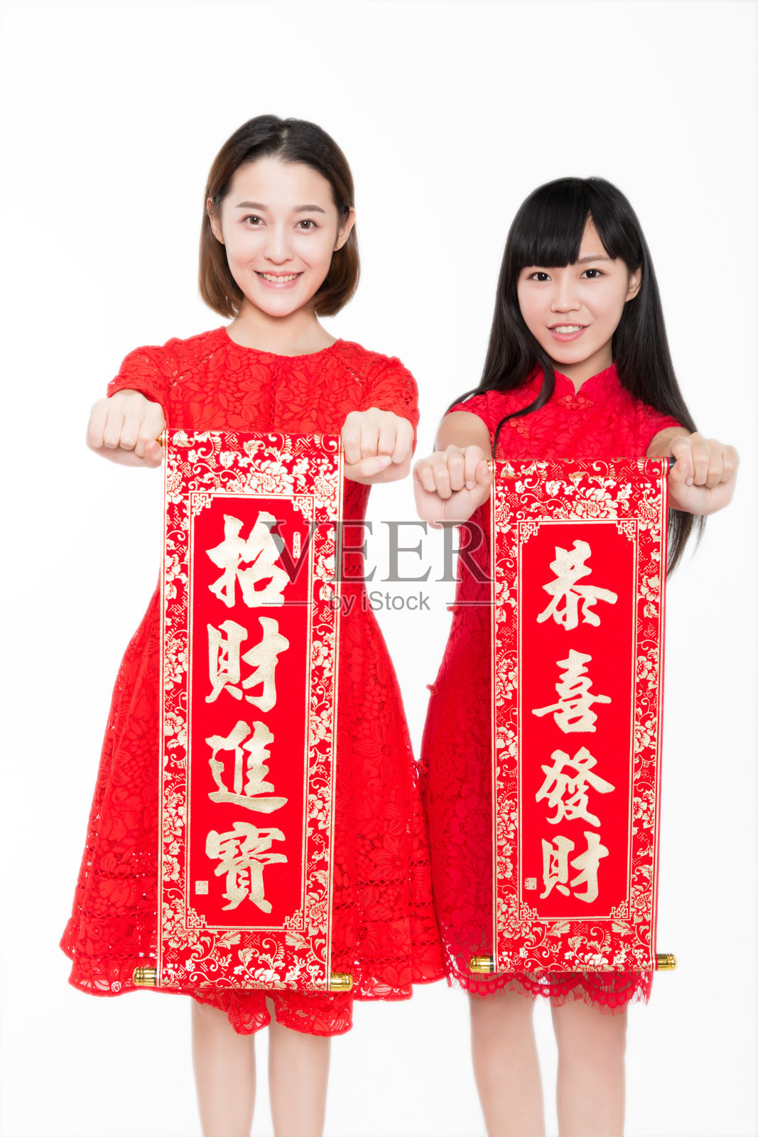 两个年轻的女人拿着中国对联，微笑着对着镜头照片摄影图片