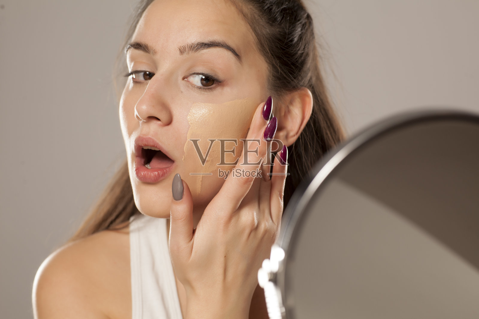 一位年轻女子用手指在脸上涂抹粉底液照片摄影图片