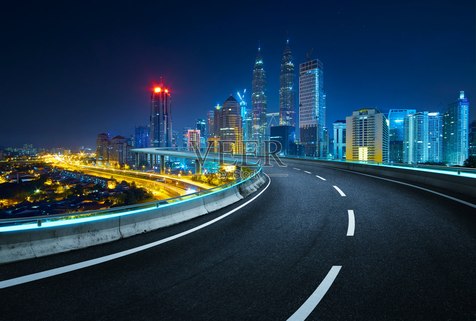 以现代城市为背景的蓝色霓虹灯设计高速公路立交桥。夜景。照片摄影图片