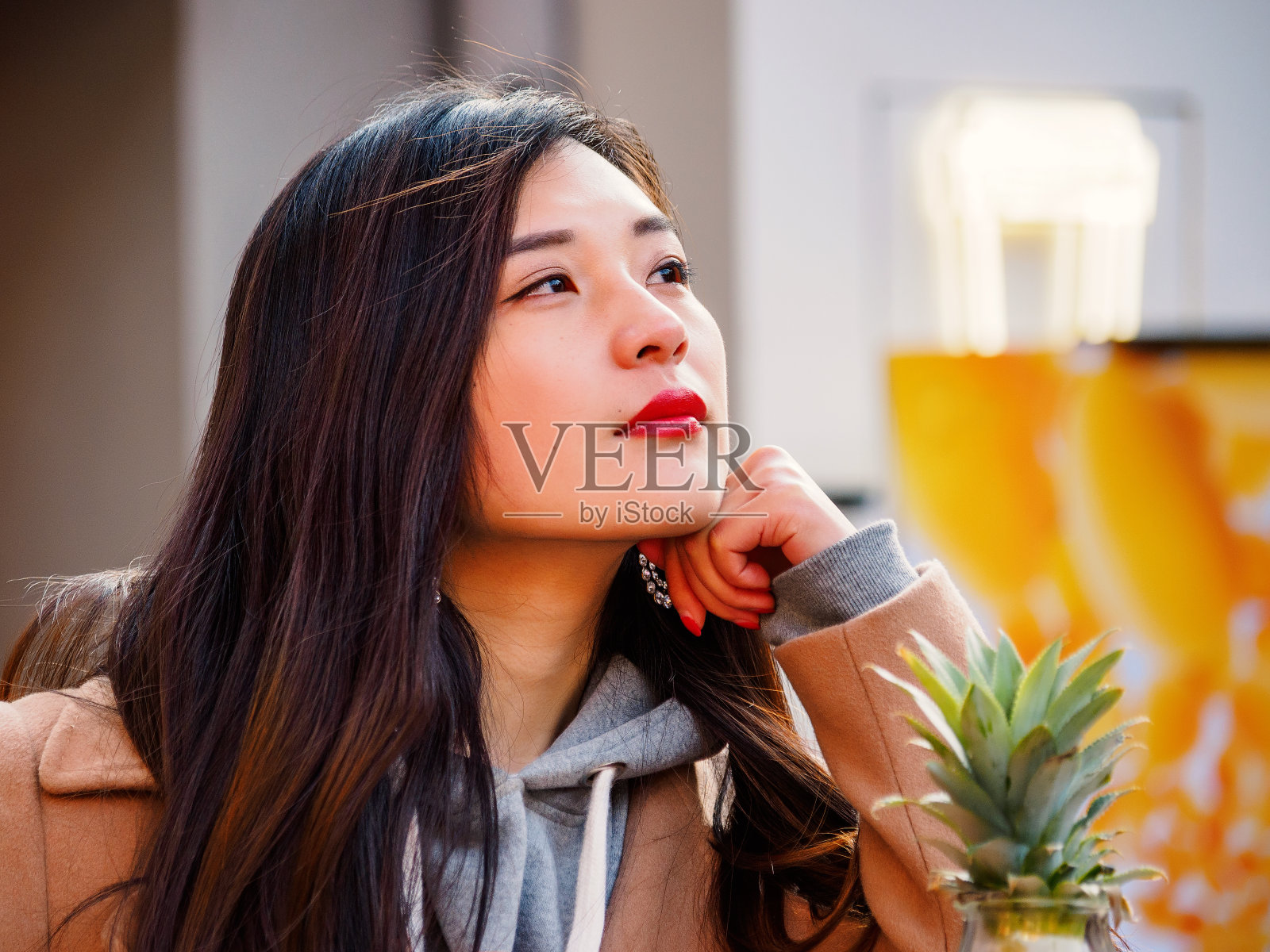 一个性感的中国年轻女孩坐在上海新天地的咖啡馆里，做着白日梦。照片摄影图片