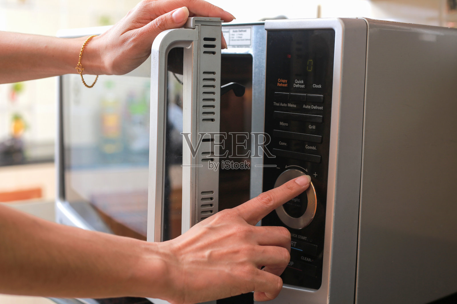 女人的手关闭微波炉门和在微波炉中准备食物。照片摄影图片