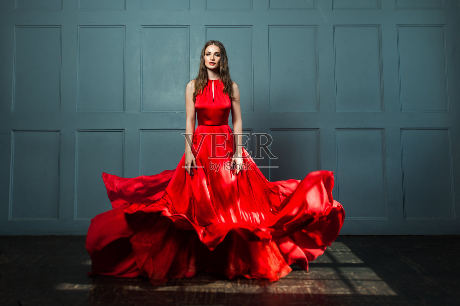 穿红裙的完美女人。美丽的时尚模特在蓝色背景照片摄影图片