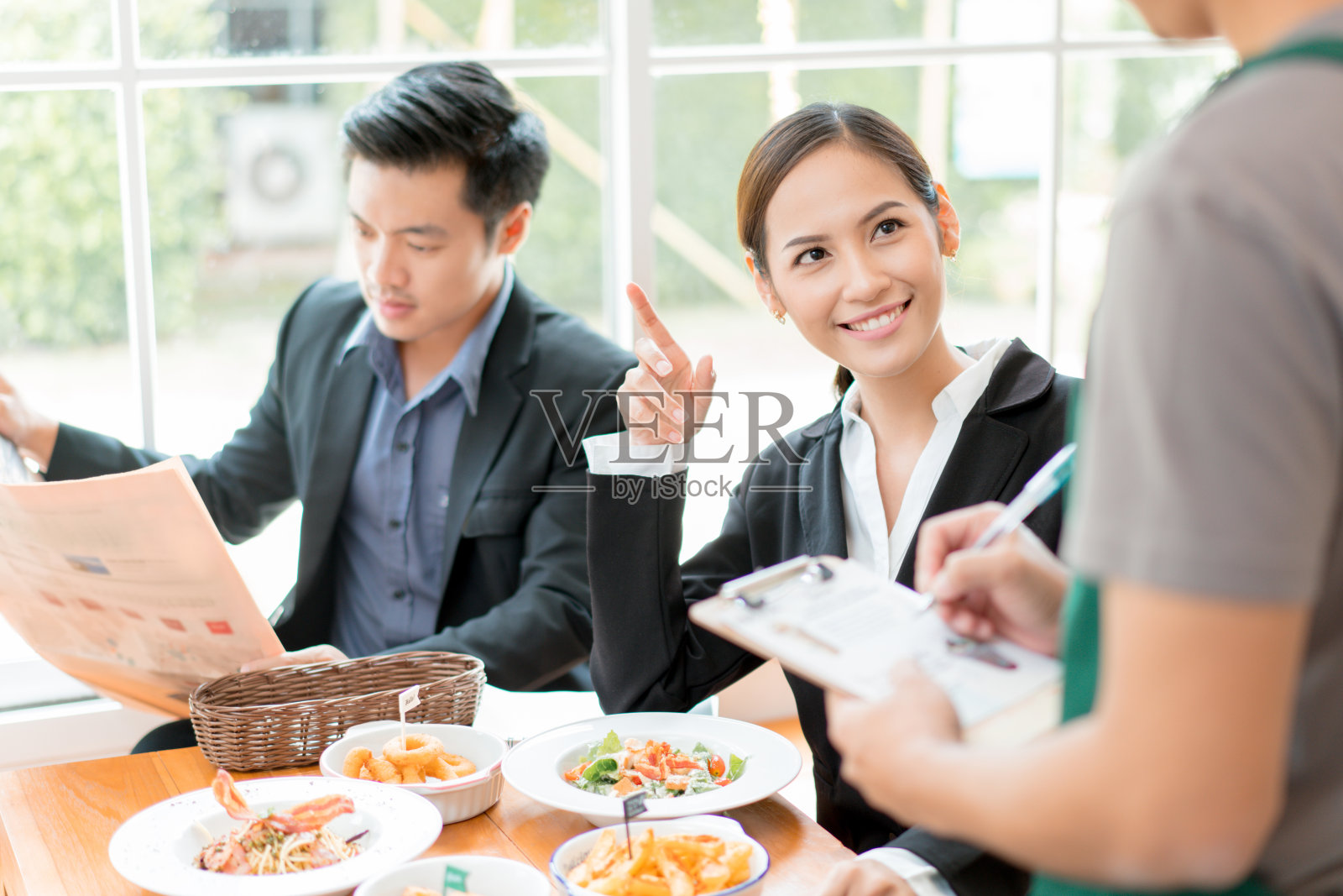 亚洲商务人士正在一家餐馆吃午饭。她在向服务员点菜照片摄影图片