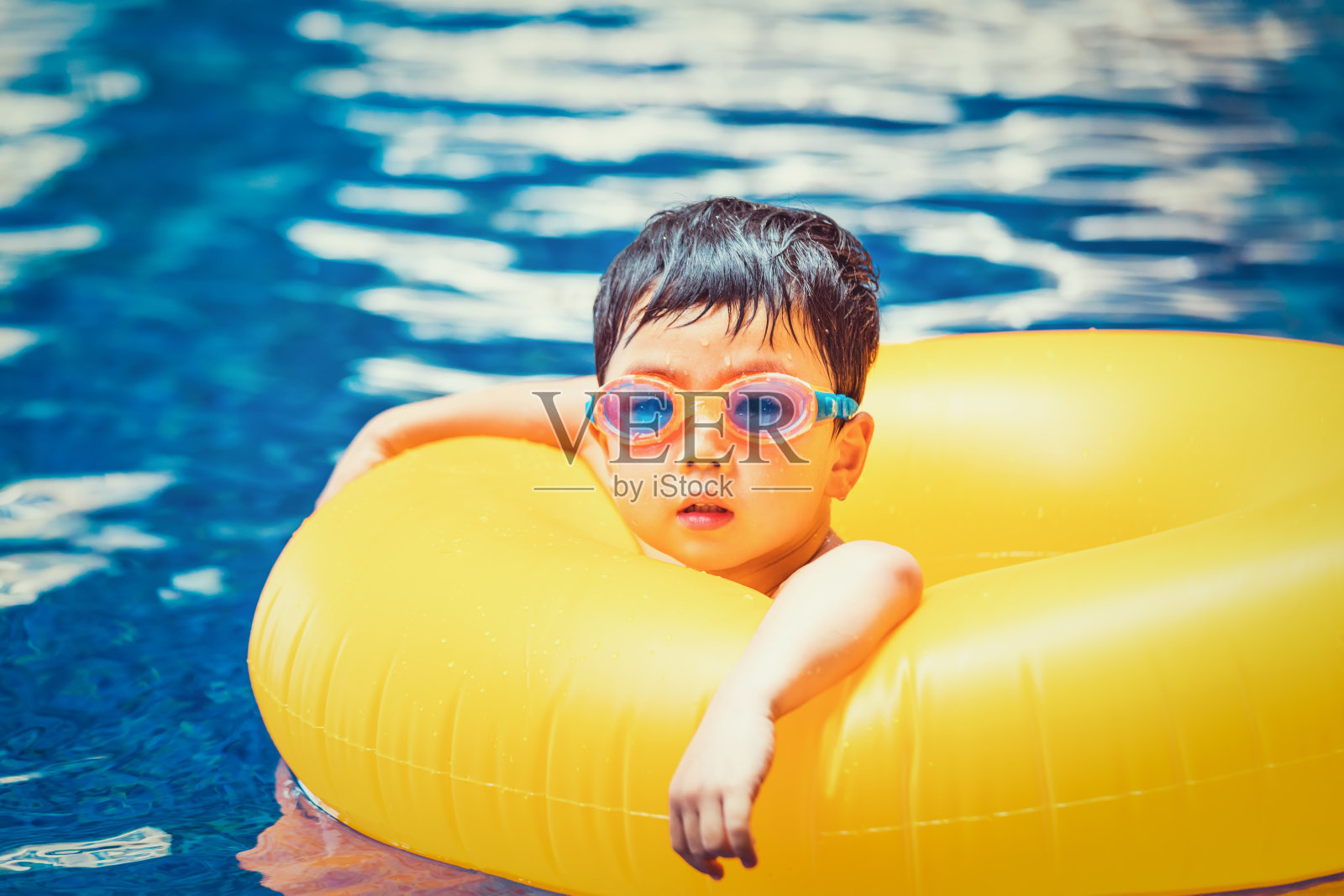 一个兴高采烈的孩子在游泳池里游泳照片摄影图片
