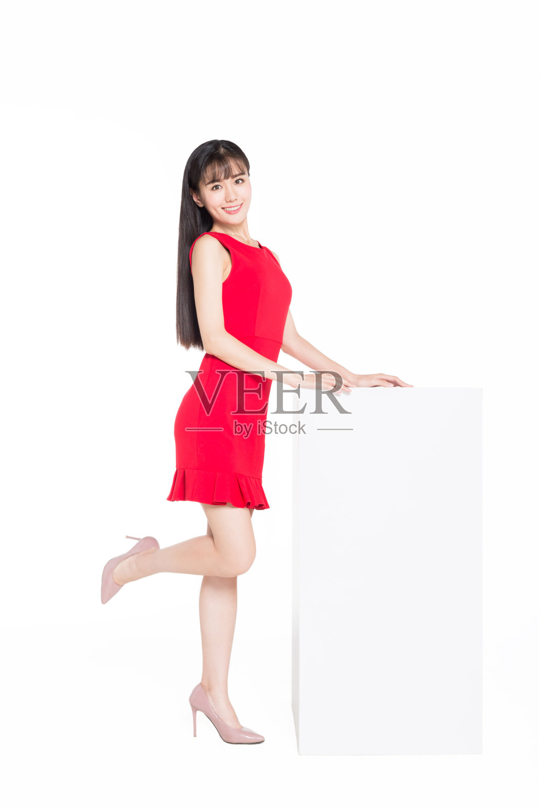 迷人的亚洲女人穿着红色的衣服摆姿势由一个白色的物体照片摄影图片