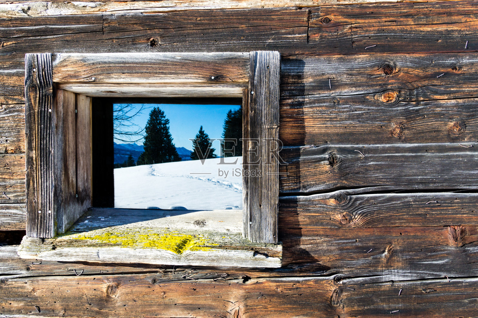 老木屋的古色古香的窗户映照出冬日的山景。木制的乡村背景。照片摄影图片