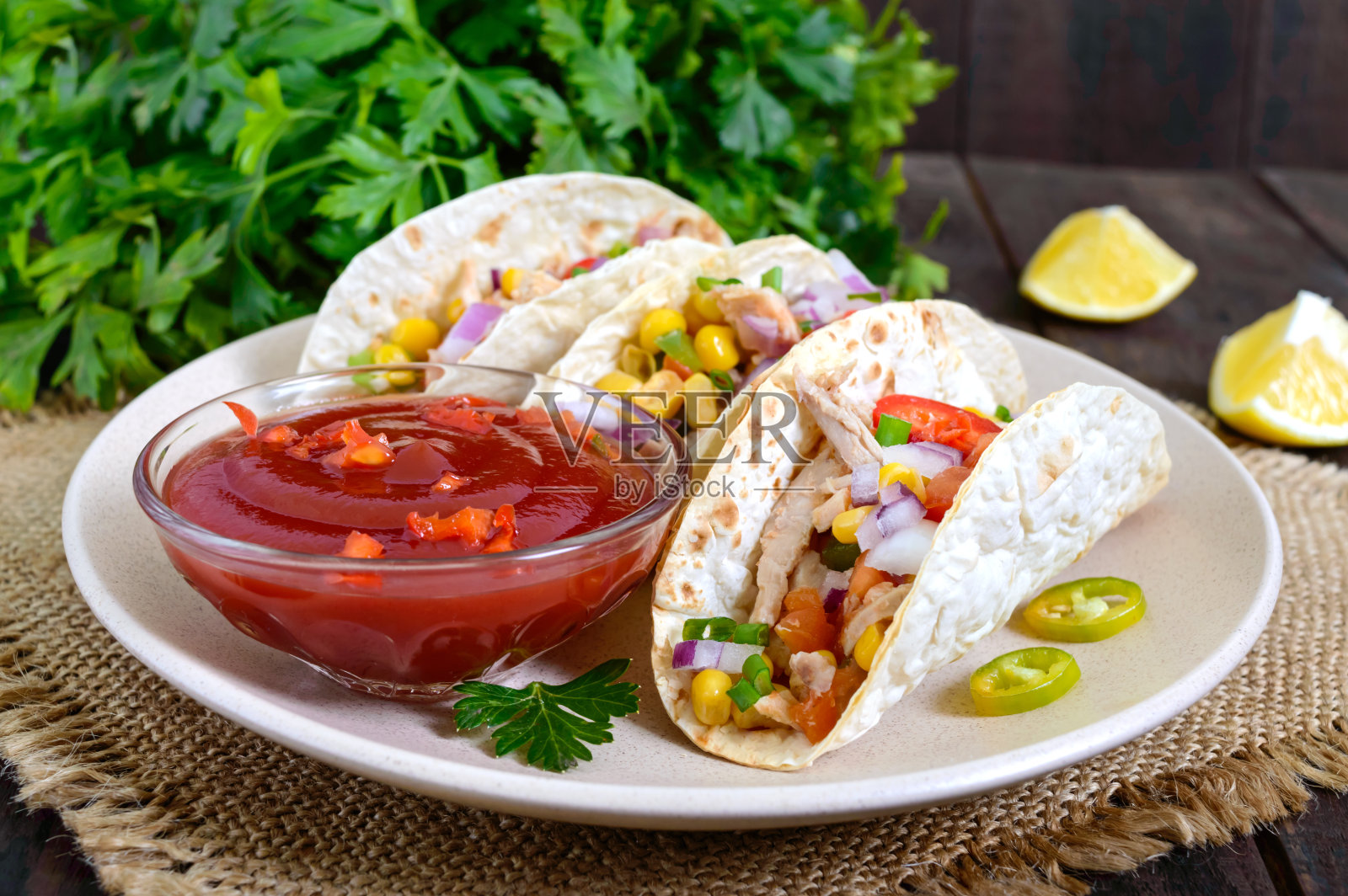 玉米饼-小麦玉米饼与肉，蔬菜，绿色和玉米与蕃茄酱在黑暗的木制背景。传统的墨西哥菜。照片摄影图片