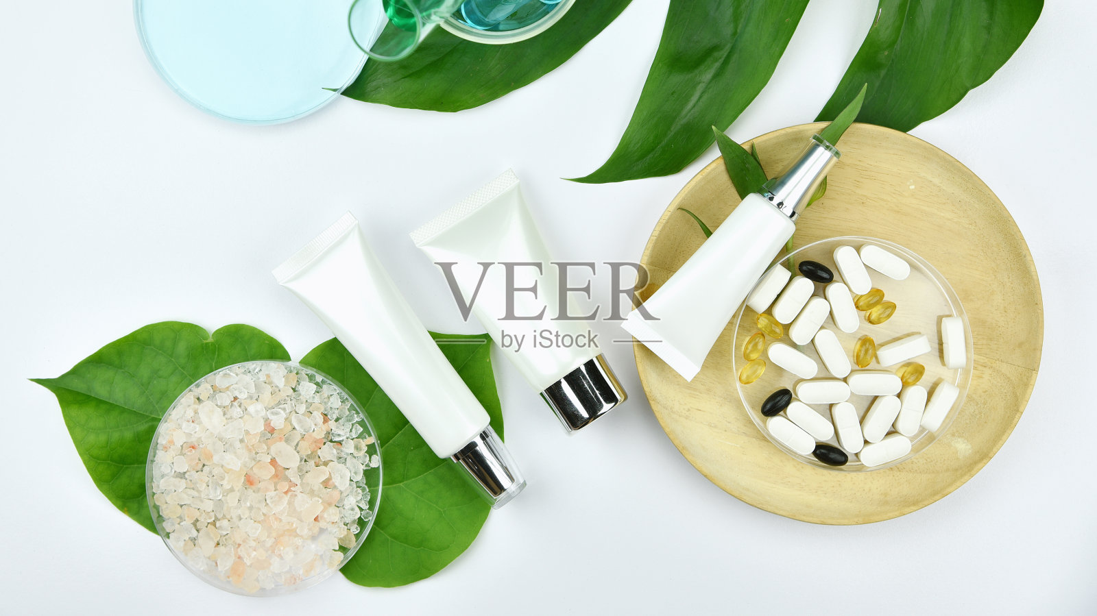 化妆品瓶容器与绿色草药叶子，空白标签的品牌模型，自然美容产品的概念。照片摄影图片