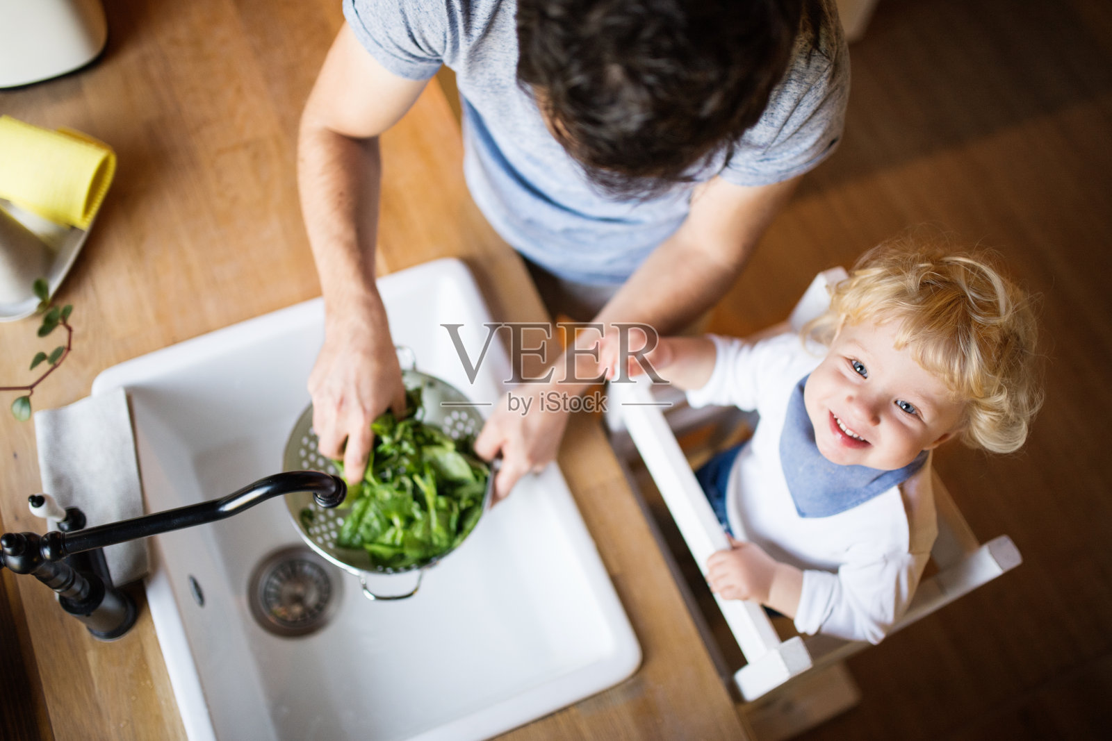 年轻的父亲和一个蹒跚学步的男孩做饭。照片摄影图片
