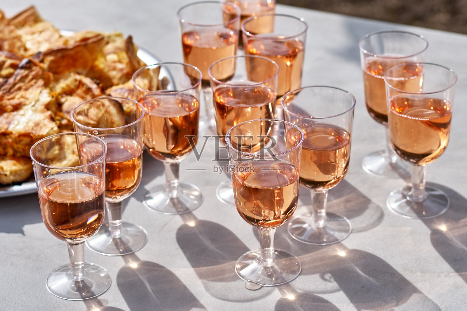 清新的粉红葡萄酒装在玻璃杯里，蛋糕放在桌上，背景是葡萄园。酿酒的概念。照片摄影图片