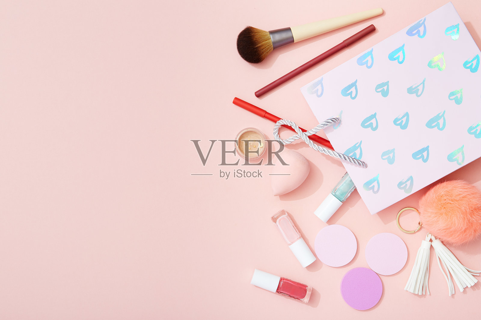 美容产品和礼品袋平铺在粉红色的背景上照片摄影图片