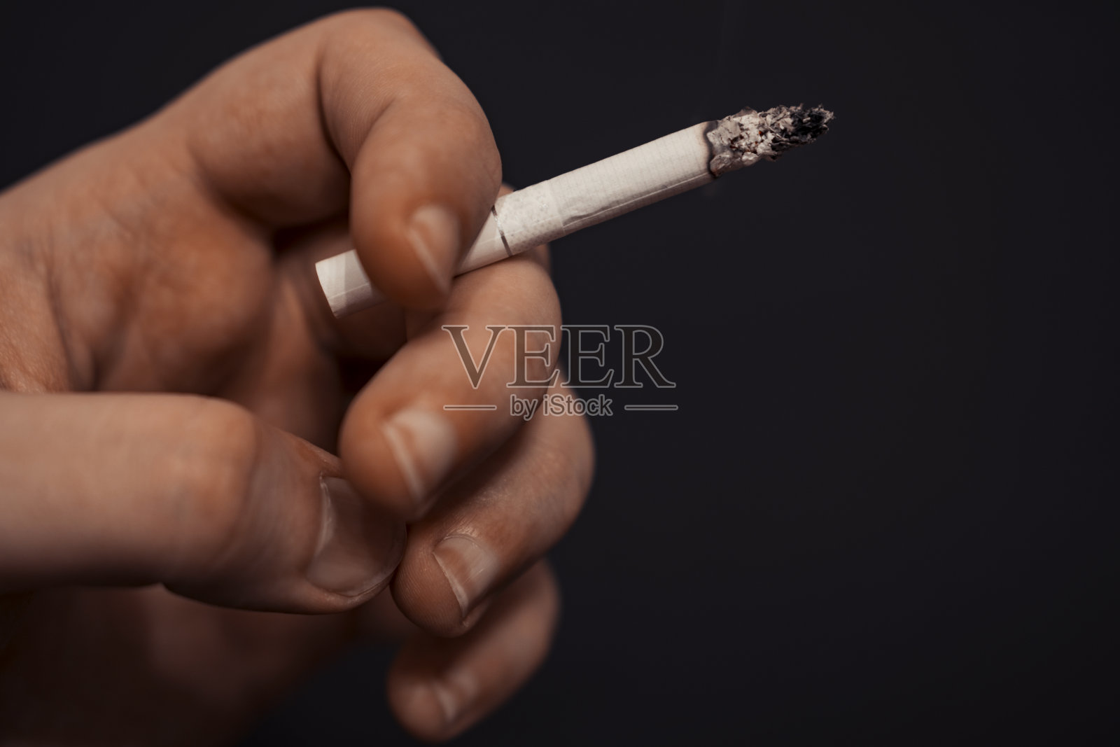 一个男人的手拿着香烟。照片摄影图片