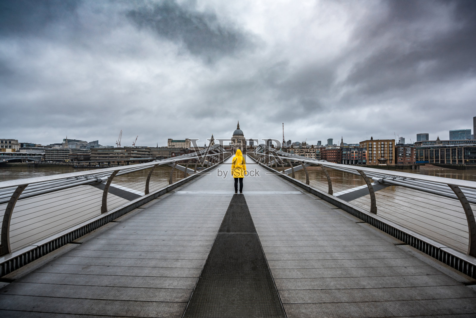 英国伦敦的一座桥上穿着黄色雨衣。照片摄影图片